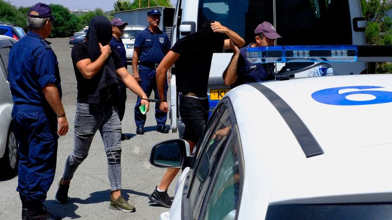 Des hommes israéliens se couvrent le visage avec leur chemise à leur arrivée au palais de justice de Famagouste, dans la ville de Paralamni, à Chypre.