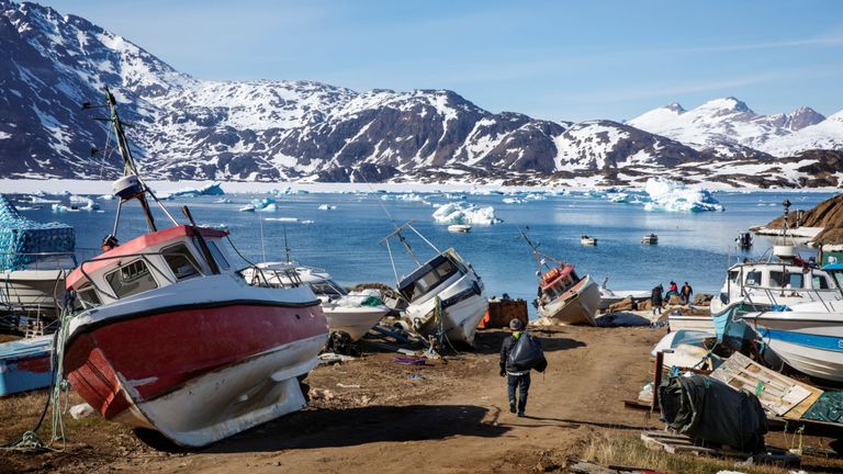 Un homme s'approche de son bateau et passe devant un certain nombre de bateaux abandonnés et en cale sèche dans la ville de Tasiilaq, au Groenland, le 15 juin 2018. REUTERS / Lucas Jackson 