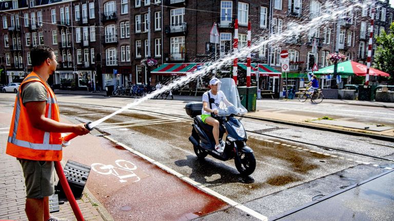 Un officier municipal arrose le pont de Wiegbrug à Amsterdam pour arroser la route