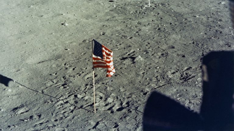 Le drapeau des États-Unis est planté à la surface de la Lune par les astronautes de la mission d’atterrissage lunaire Apollo 11 de la NASA, vus de l’intérieur du module lunaire l’Aigle, le 20 juillet 1969. à l'arrière-plan, la caméra de télévision en surface lunaire en noir et blanc sur laquelle les astronautes télévisés Neil Armstrong et Edwin 'Buzz & # 39;' Aldrin Jr au cours de leur EVA (activité extravéhiculaire). (Photo par Space Frontiers / Getty Images)
