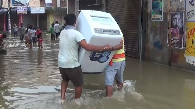 Les hommes portent un réfrigérateur loin des eaux de crue