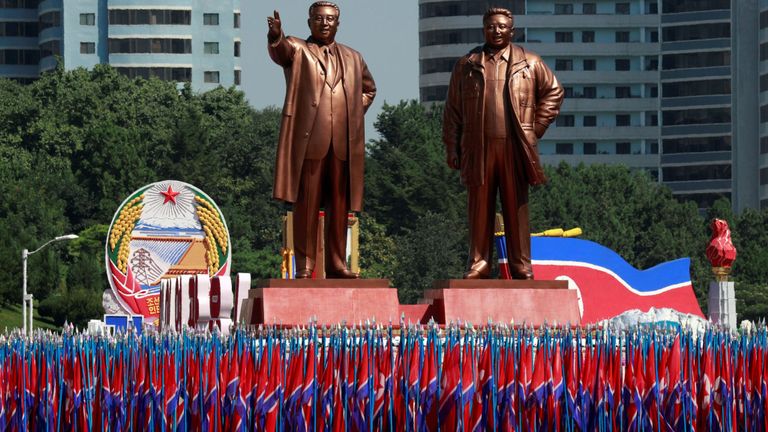 Les gens portent des drapeaux devant les statues de la fondatrice nord-coréenne Kim Il Sung (à gauche) et du défunt dirigeant Kim Jong Il lors d'un défilé militaire marquant le 70e anniversaire de la fondation de la Corée du Nord à Pyongyang (Corée du Nord), le 9 septembre 2018