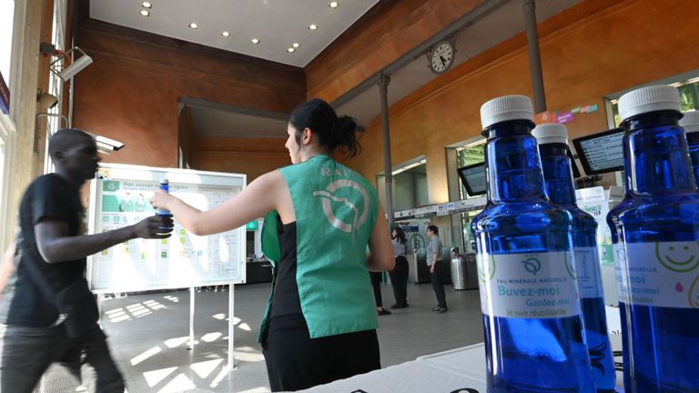 Un agent de la RATP (Opérateur Autonome des Transports Parisiens) distribue des bouteilles d'eau aux navetteurs à Paris le 23 juillet 2019