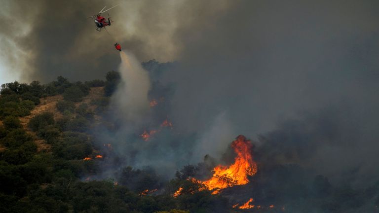 Un hélicoptère lâche de l'eau pour distinguer un feu de forêt à Toledo en Espagne