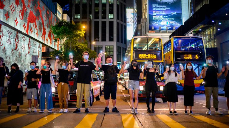 Les gens se tiennent la main et utilisent leurs torches téléphoniques pour former une chaîne humaine le long d'un passage pour piétons à Hong Kong le 23 août 2019