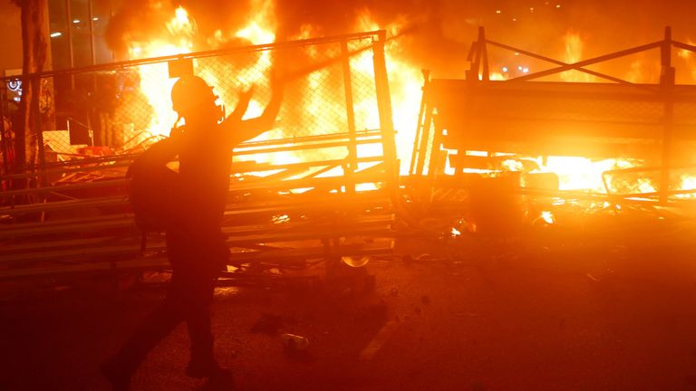 Un manifestant se tient à côté d'une barricade en feu 