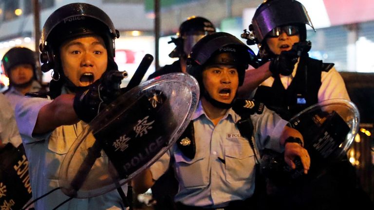 La police de Hong Kong pointe des armes de poing sur les manifestants.