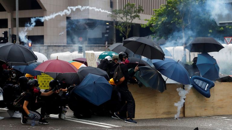 Des manifestants se mettent à l'abri alors que la police tire des gaz lacrymogènes lors de la manifestation de samedi à Hong Kong.
