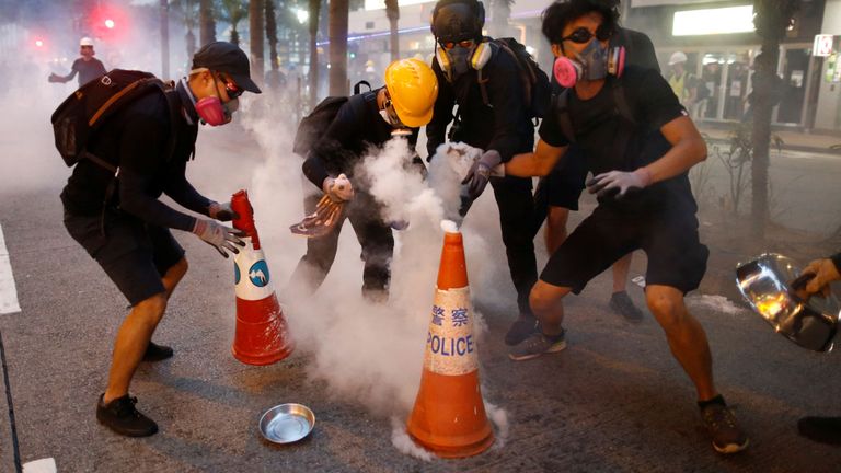 Des manifestants tentent d'éteindre des bonbonnes de gaz lacrymogène dans le quartier de Wan Chai dimanche