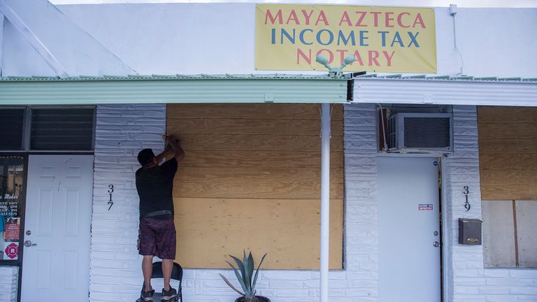 Un propriétaire d'entreprise de Floride met du contreplaqué sur les fenêtres de son bureau alors qu'il se prépare à l'arrivée de l'ouragan Dorian