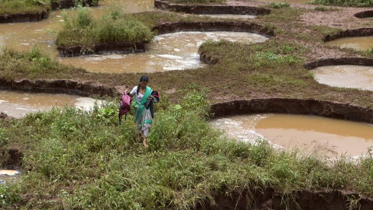 Une femme porte ses affaires devant les nids-de-poule créés par les fortes pluies dans un village du Maharashtra
