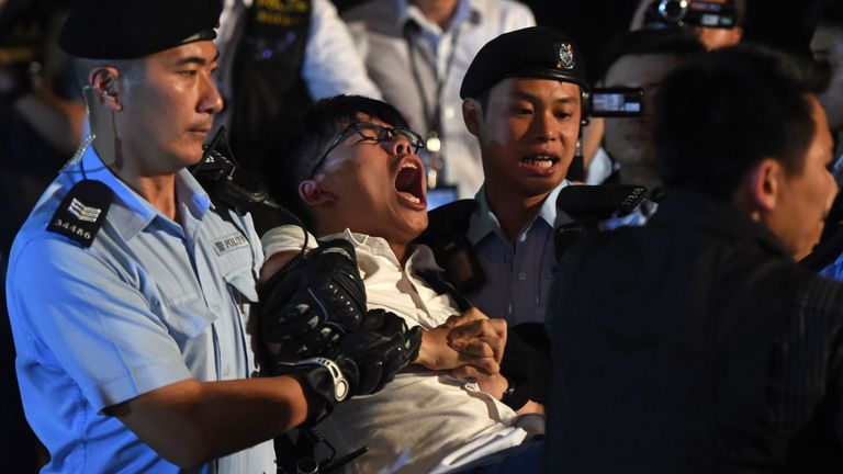 Joshua Wong (C), militant pour la cause de la démocratie, hurle alors qu'il est emmené par la police après que lui-même et d'autres manifestants ont organisé un sit-in pour protester contre la statue de Golden Bauhinia, remise à Hong Kong par la Chine pour marquer le transfert en 1997, devant la Centre de congrès et d'expositions à Hong Kong le 28 juin 2017