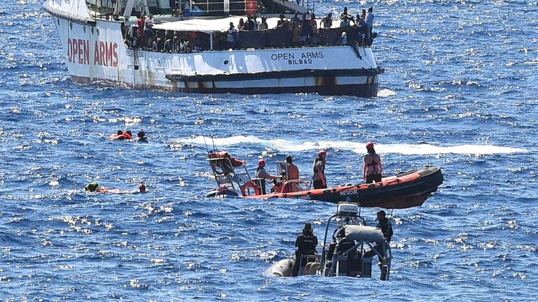 Des migrants nagent après avoir sauté du navire de sauvetage espagnol Open Arms, près de la côte italienne à Lampedusa, en Italie 