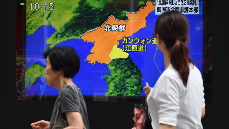 Au Japon, des piétons passent devant un écran de télévision au bord de la route pour rendre compte du lancement de projectiles par la Corée du Nord. 