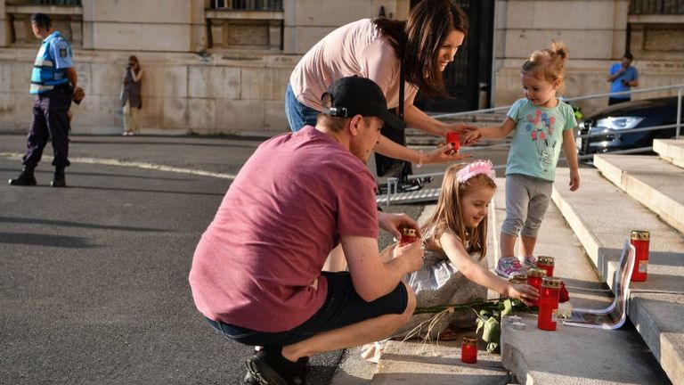 Une famille allume des bougies à Bucarest à côté d'un portrait d'Alexandra