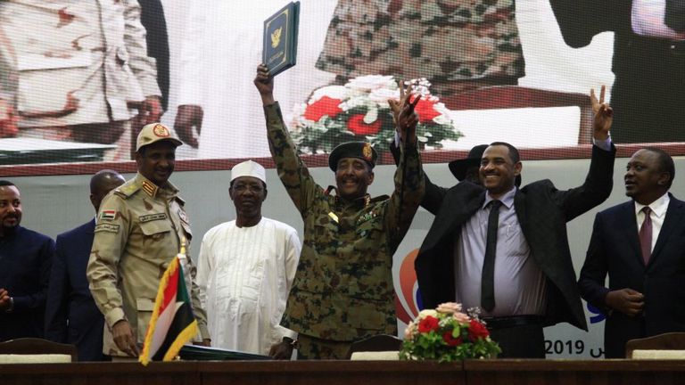 Le leader du mouvement de protestation soudanais Ahmad Rabie (2e au rang), affiche le geste de victoire aux côtés du général Abdel Fattah al-Burhan (C), chef du Conseil militaire transitoire au Soudan. 