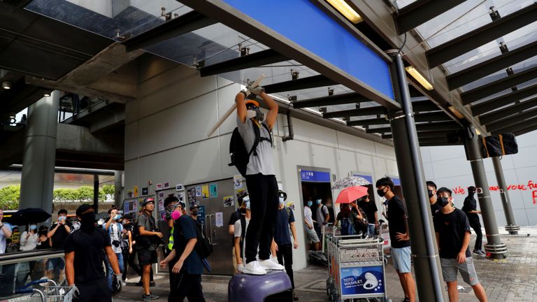 Un manifestant casse une caméra de sécurité devant l'aéroport international de Hong Kong
