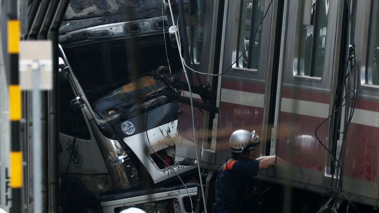 Des secouristes, des policiers et des employés de la compagnie de chemin de fer travaillent sur les lieux après le déraillement du train lors de la collision avec le camion à Yokohama, près de Tokyo.