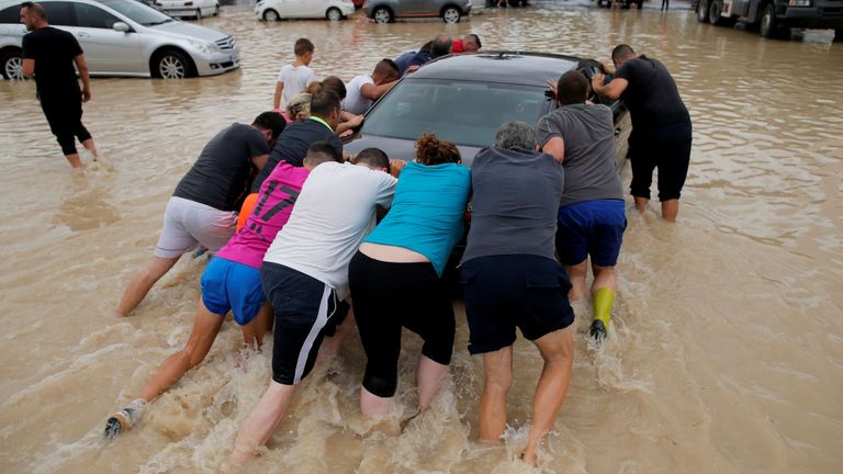 Des gens poussent une voiture dans un parking partiellement submergé alors que des pluies torrentielles s'abattent sur Orihuela, en Espagne.