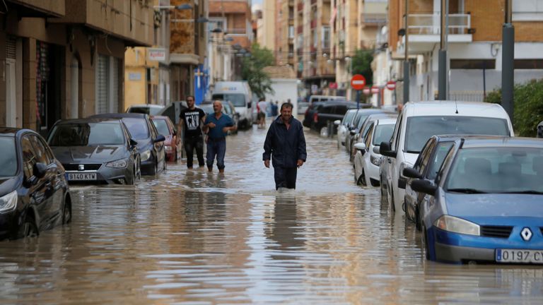Les gens marchent dans une rue inondée alors que des pluies torrentielles s'abattent sur Orihuela