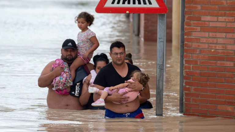Des gens transportent des enfants dans une rue inondée à Almoradi 