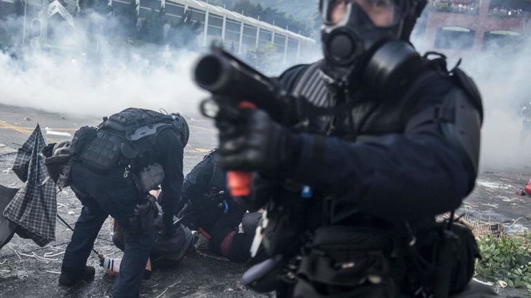 Un officier de police anti-émeute pointe son lanceur de projectiles alors que ses collègues arrêtent des manifestants dans le district de Sha Tin à Hong Kong le 1er octobre 2019