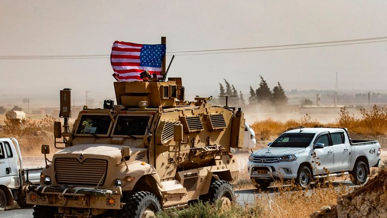 Un soldat américain assis au sommet d'un véhicule blindé lors d'une manifestation des Kurdes syriens contre les menaces turques près d'une base pour la coalition internationale dirigée par les États-Unis à la périphérie de la ville de Ras al-Ain dans la province syrienne de Hasakeh, près de la frontière turque, le 6 octobre 2019 - Les forces américaines en Syrie ont commencé à se retirer aujourd'hui des zones frontalières avec la Turquie, ouvrant la voie à la menace d'invasion militaire à Ankara et faisant craindre une recrudescence des djihadistes. (Photo de Delil SOULEIMAN / AFP) (Photo de DELIL SOULEIMAN / AFP via Getty Images)