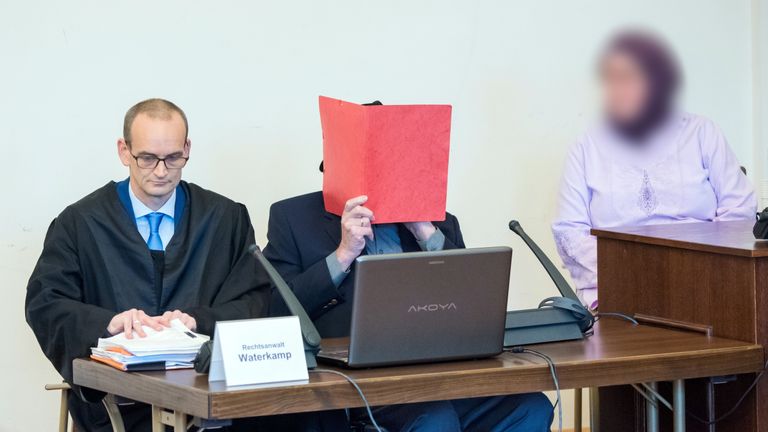 Bruno Dey (C), ancien SS, âgé de 93 ans, se couvre le visage et est assis à côté de son avocat, Stefan Waterkamp (à gauche) et d'un membre de la famille (à droite) dans la salle d'audience lors de son procès à Hambourg le 21 octobre 2019. - Dey se tient debout accusé d'implication dans le meurtre de 5 230 personnes alors qu'il travaillait au camp de concentration de Stutthof, près de l'actuelle Dantzig, aujourd'hui Gdansk en Pologne. (Photo de Daniel Bockwoldt / POOL / AFP) (Photo de DANIEL BOCKWOLDT / POOL / AFP via Getty Images)