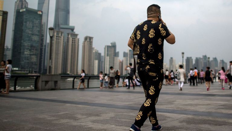 Cette photo prise le 15 juillet 2016 montre un homme portant une tenue avec des symboles du dollar en or alors qu'il marchait dans le Bund, surplombant le quartier financier de Pudong à Shanghai. La croissance du PIB de la Chine au deuxième trimestre est restée stable à 6,7%, a annoncé le gouvernement le 15 juillet, alors que la deuxième économie mondiale cherche la stabilité face à la noirceur croissante des perspectives mondiales.