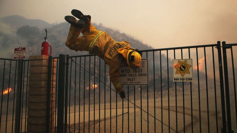Un pompier saute par-dessus une porte verrouillée près du feu de Tick dans le sud de la Californie