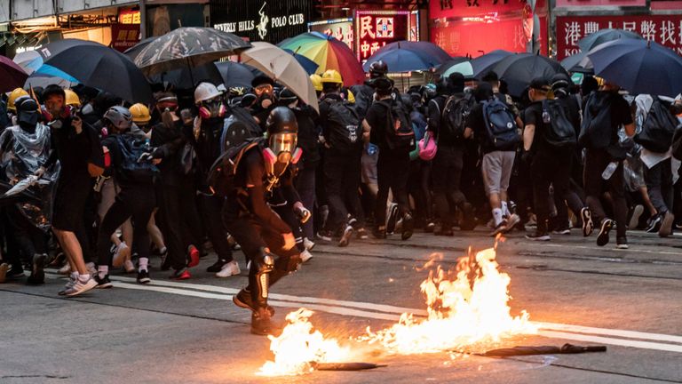 Un manifestant masqué pro-démocratie lance un cocktail Molotov lors d'un affrontement avec la police