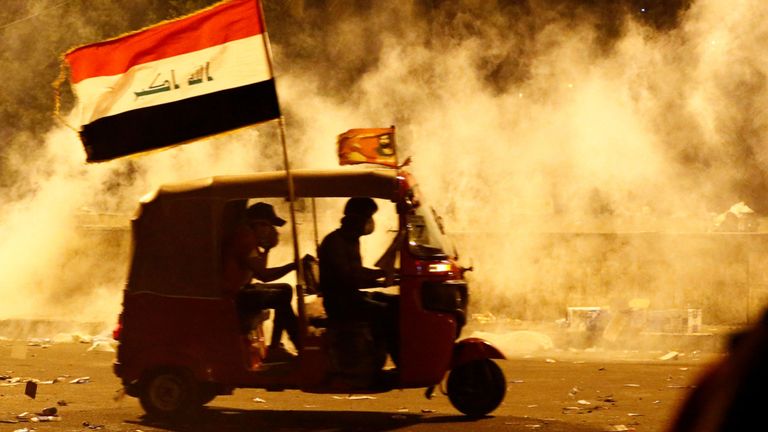 Un tuk-tuk éloigne du gaz lacrymogène tiré par les forces de sécurité irakiennes lors d'une manifestation contre la corruption, le manque d'emplois et la médiocrité des services, à Bagdad, en Irak, le 26 octobre 2019
