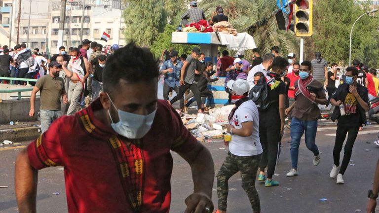 Des manifestants irakiens fuient des gaz lacrymogènes à Bagdad