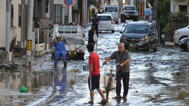 Les résidents locaux nettoient une rue inondée à la suite du typhon Hagibis à Kawasaki le 13 octobre 2019