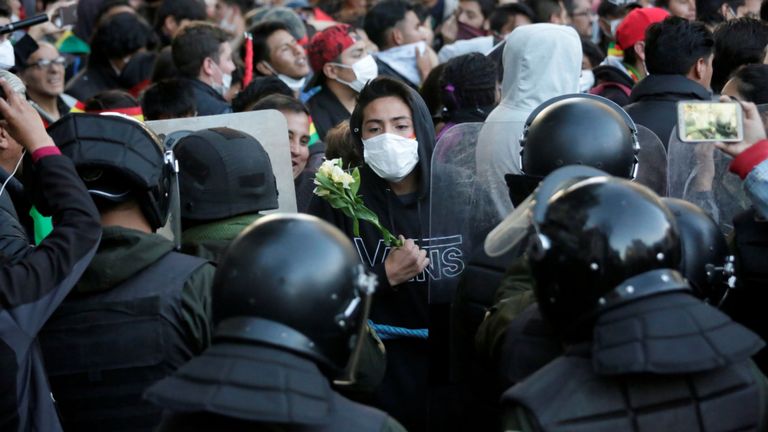 Un manifestant détient des fleurs alors qu'il se tenait devant la police lors d'une manifestation à La Paz, en Bolivie, le 22 octobre 2019