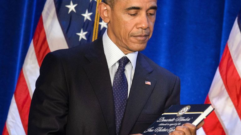 Le président des États-Unis, Barack Obama, détient une copie de l'accord sur le nucléaire iranien présenté par la chef de la minorité à la Chambre, Nancy Pelosi (D-CA), lors de la conférence sur les questions démocratiques à la Chambre, le 28 janvier 2016 à Baltimore, Maryland. / AFP / Brendan Smialowski (Le crédit photo doit se lire comme suit: BRENDAN SMIALOWSKI / AFP / Getty Images)