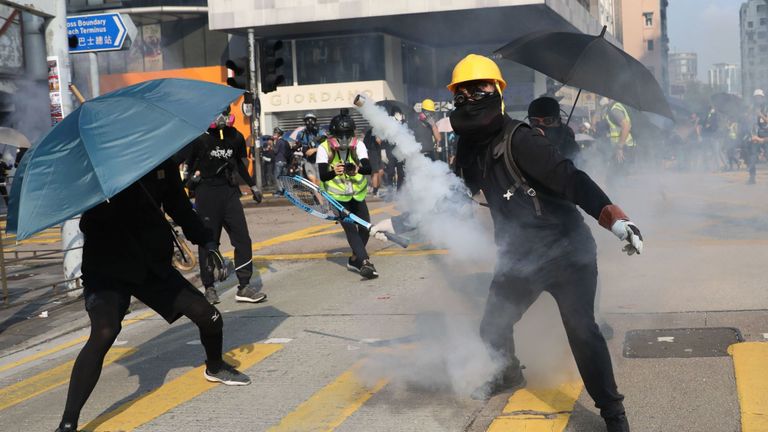 Un manifestant se prépare à frapper une cartouche de gaz lacrymogène avec une raquette de tennis à Hong Kong