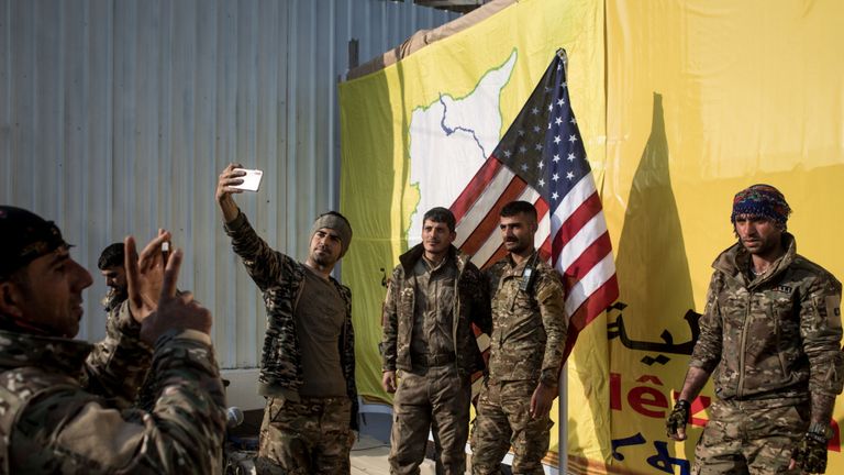 BAGHOUZ, SYRIE - 23 MARS: Des combattants des Forces démocratiques syriennes (SDF) posent pour une photo avec le drapeau américain sur scène après la cérémonie de victoire du SDF annonçant la défaite de l'EIIL à Baghouz, qui s'est tenue à Omer Oil Field le 23 mars 2019 à Baghouz, Syrie. Les Forces de défense syriennes (SDF) dirigées par les Kurdes et soutenues par les Américains ont déclaré samedi 