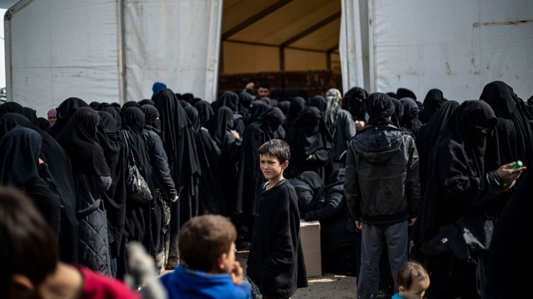 Des réfugiées irakiennes et des femmes syriennes déplacées vivant dans le camp d'al-Hol abritant des membres de la famille d'un membre de l'État islamique (IS), font la queue pour recevoir des marchandises dans le camp situé dans le gouvernorat d'al-Hasakeh, dans le nord-est de la Syrie, le 28 mars 2019.