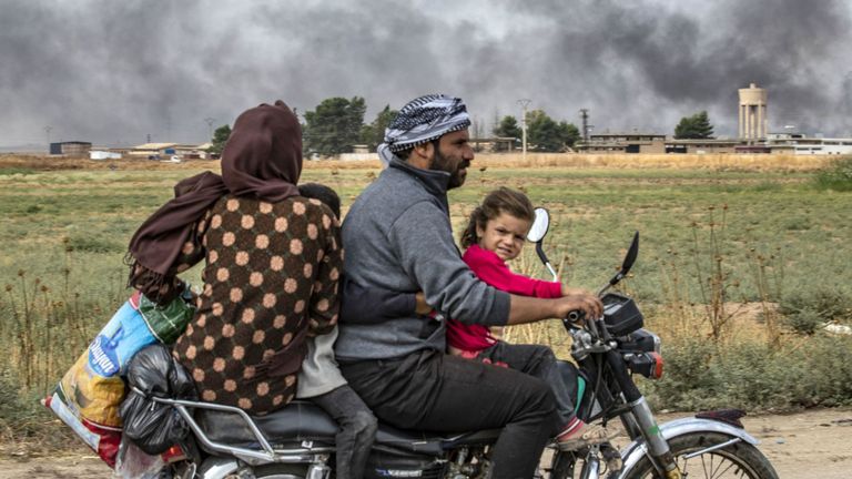 Des membres d'une famille syrienne utilisent une moto pour fuir la campagne de la ville de Ras al-Ain au nord-est de la Syrie, à la frontière turque, en direction de l'ouest de la ville de Tal Tamr, le 19 octobre 2019. La fumée derrière eux provient de pneus en feu. utilisé pour gêner la visibilité des avions de guerre. - Le président turc Recep Tayyip Erdogan a lancé un nouvel avertissement aujourd'hui pour "écraser" les forces kurdes alors que les deux parties échangeaient des accusations de violation du traité de trêve négocié par les États-Unis dans le nord-est de la Syrie. (Photo par Delil SOULEI