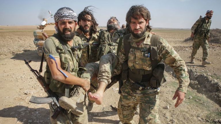 Des rebelles syriens soutenus par la Turquie transportent un combattant blessé alors qu'ils combattaient des Kurdes syriens dans la ville frontalière de Tal Abyad