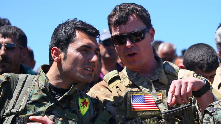 Un officier américain s’entretient avec un combattant des unités de protection du peuple kurde près de la ville de Derik, dans le nord-est de la Syrie.