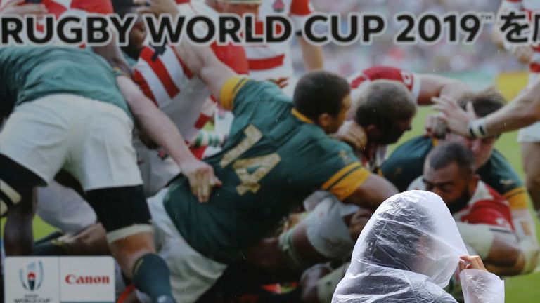 Une femme passe devant un panneau publicitaire de la Coupe du monde de rugby dans le Shinagawa