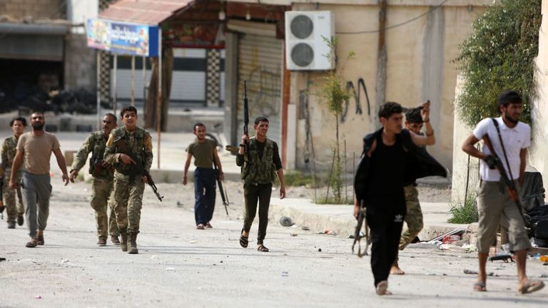 Des combattants syriens soutenus par la Turquie marchent dans une rue proche de leur position dans la ville syrienne de Ras al-Ain le 19 octobre 2019. - Le président turc Recep Tayyip Erdogan a tiré aujourd'hui un nouvel avertissement " "écraser" les forces kurdes alors que les deux parties échangeaient des accusations de violation d'un accord de trêve négocié par les États-Unis dans le nord-est de la Syrie. (Photo de Nazeer Al-khatib / AFP) (Photo de NAZEER AL-KHATIB / AFP via Getty Images)
