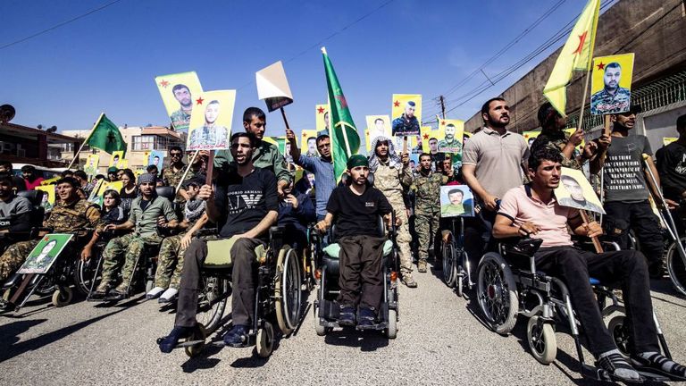 Des combattants kurdes ont tenu des photos de camarades morts alors qu'ils marchaient pour protester contre l'action militaire turque