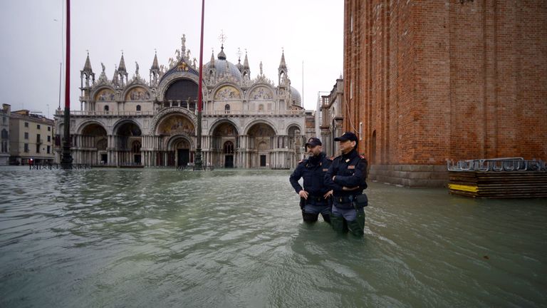 Des officiers de police italiens se tiennent sur la place inondée St Mark