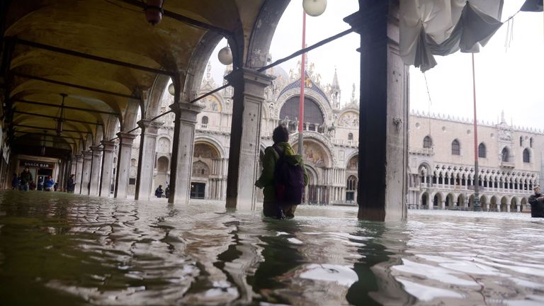 Une personne traverse une arcade inondée près de la basilique Saint-Marc