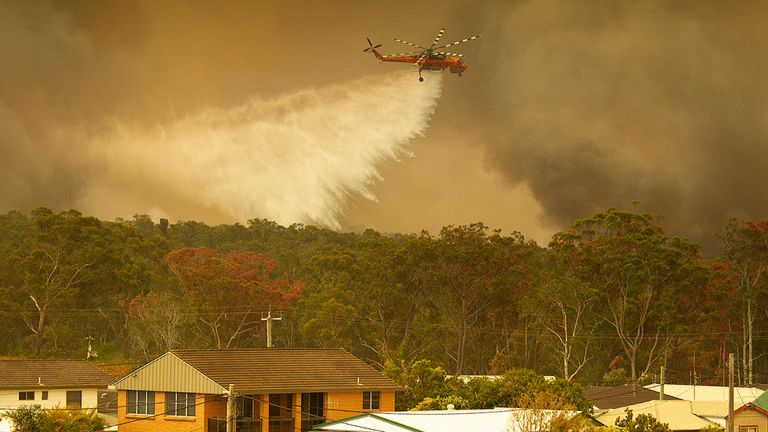 Un hélicoptère lâche de l'eau sur un feu de brousse à Harrington, sur la côte de la Nouvelle-Galles du Sud