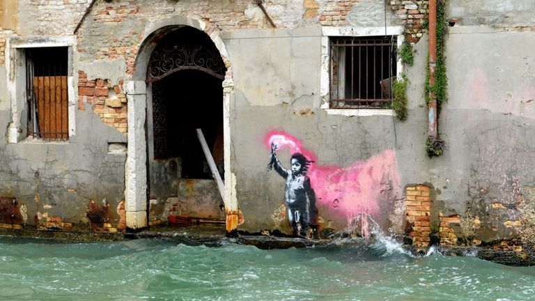 L'œuvre du street-artiste Banksy, qui représente un enfant migrant portant un gilet de sauvetage et une torche rose fluo, est photographiée le 13 novembre 2019 à Venise, après le niveau exceptionnel de la marée haute "Alta Acqua".