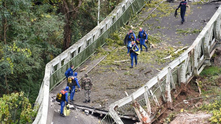Les sauveteurs marchent sur un pont suspendu qui s'est effondré lundi matin